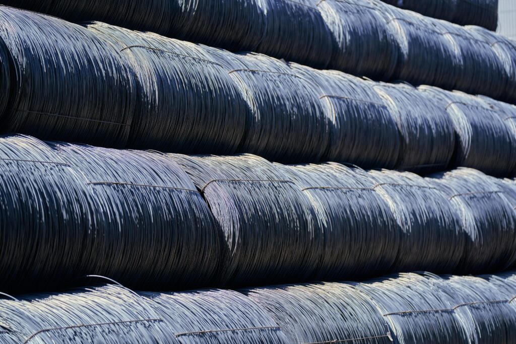 Close-up of stacked industrial steel wire coils glistening in sunlight.