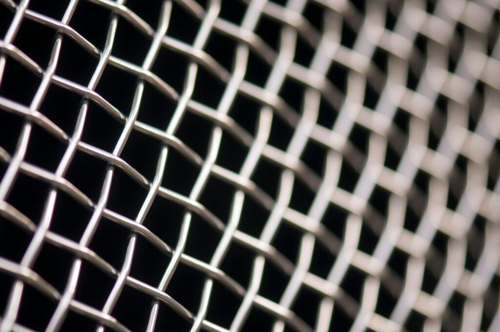 Detailed close-up of metal wire mesh pattern with a blurred background, showcasing texture and structure.